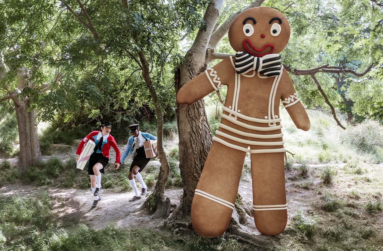 Two young adults holding hands next to a gigantic gingerbread man