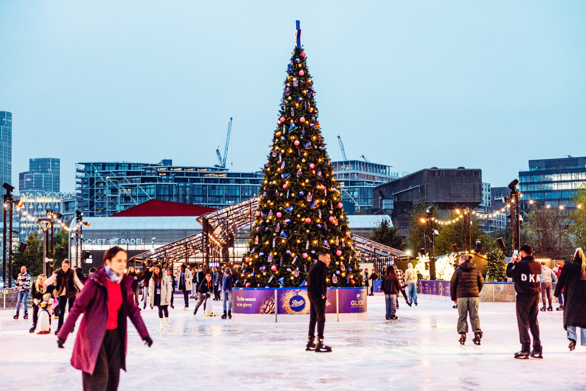 Visitors ice skating against backdrop of Christmas tree