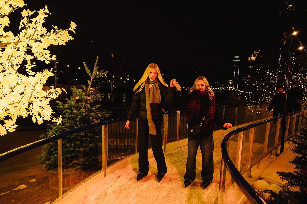 Friends holding hands and skating together on the skate trail at night