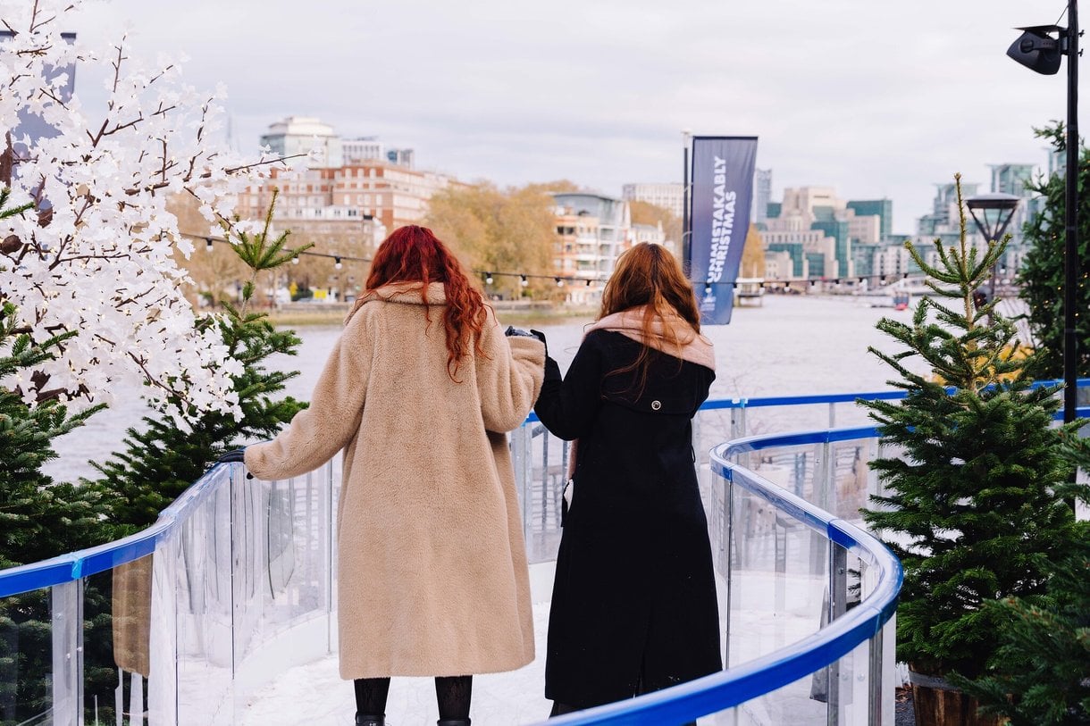 Two women skating on the skate trail, with their backs to the camera
